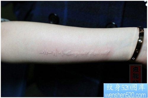 女人手臂流行时尚的白色心电图与字母纹身图片