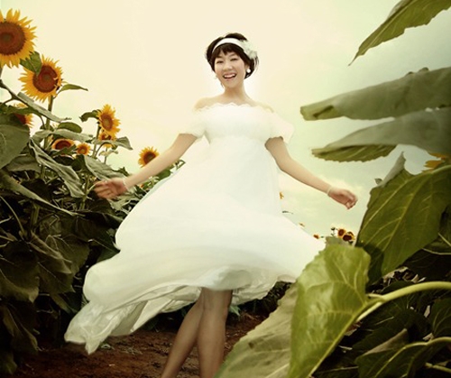 在向日葵花中拍摄写真的女生照